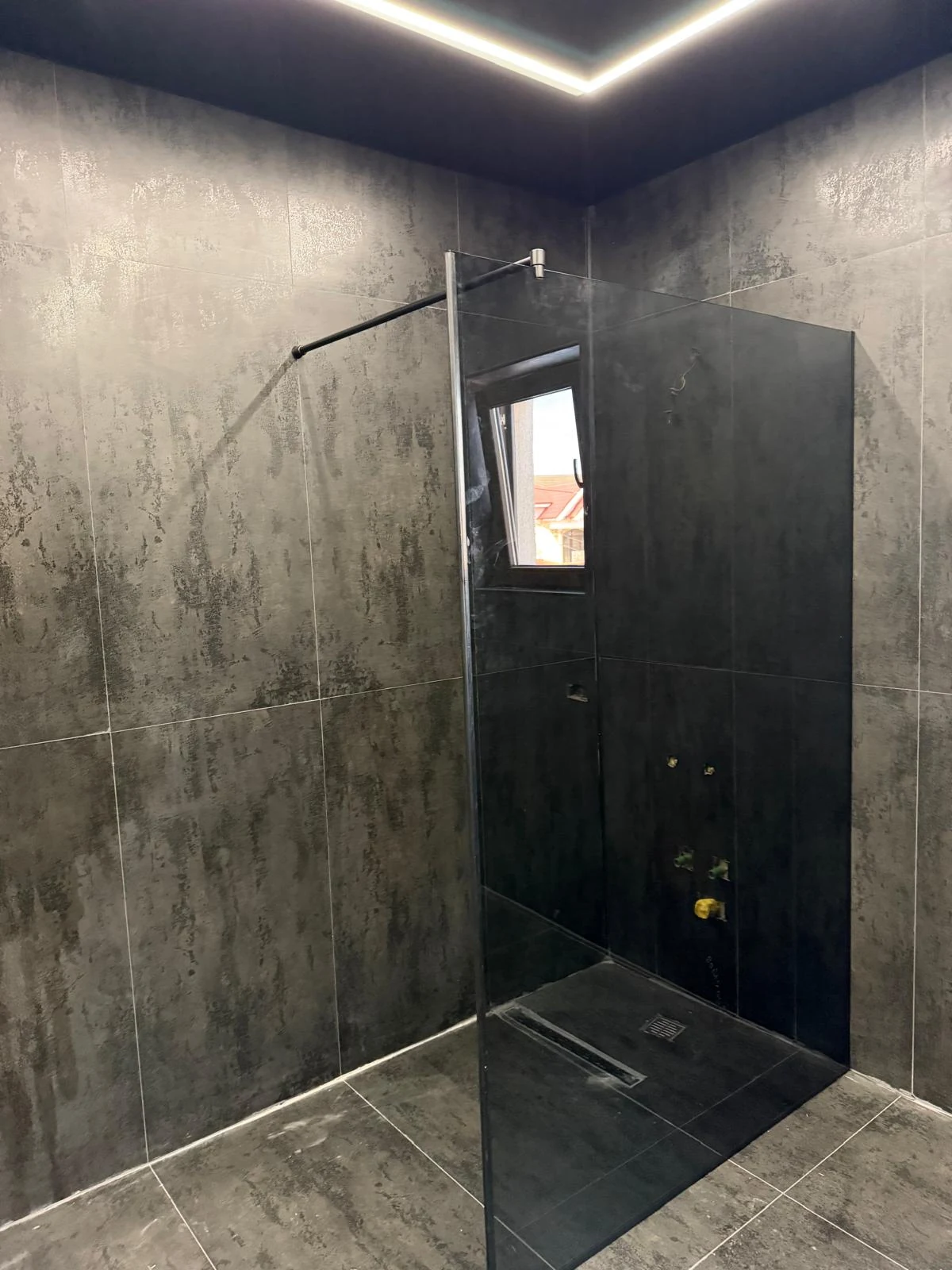 Paravan walk-in din sticlă transparentă într-o baie gri